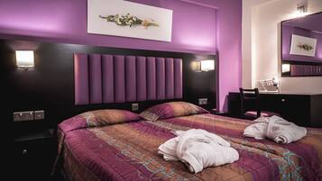A modern hotel room with a large bed, a headboard with vertical panels, a bedside table, a chair, a dresser, and a mirror.