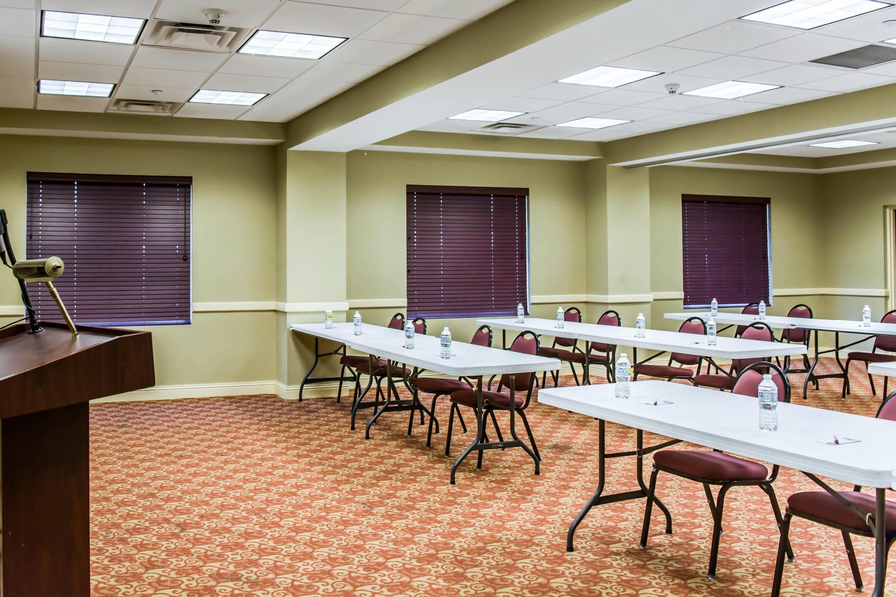 A conference room with tables, chairs, and a podium.