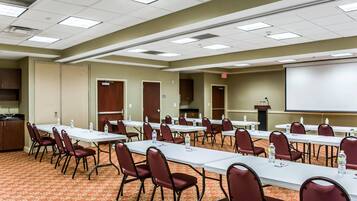 A conference room with multiple tables and chairs, a projector screen, and a podium.