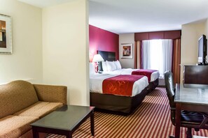 Une chambre d’hôtel avec un canapé, deux lits, un bureau et une télévision.
