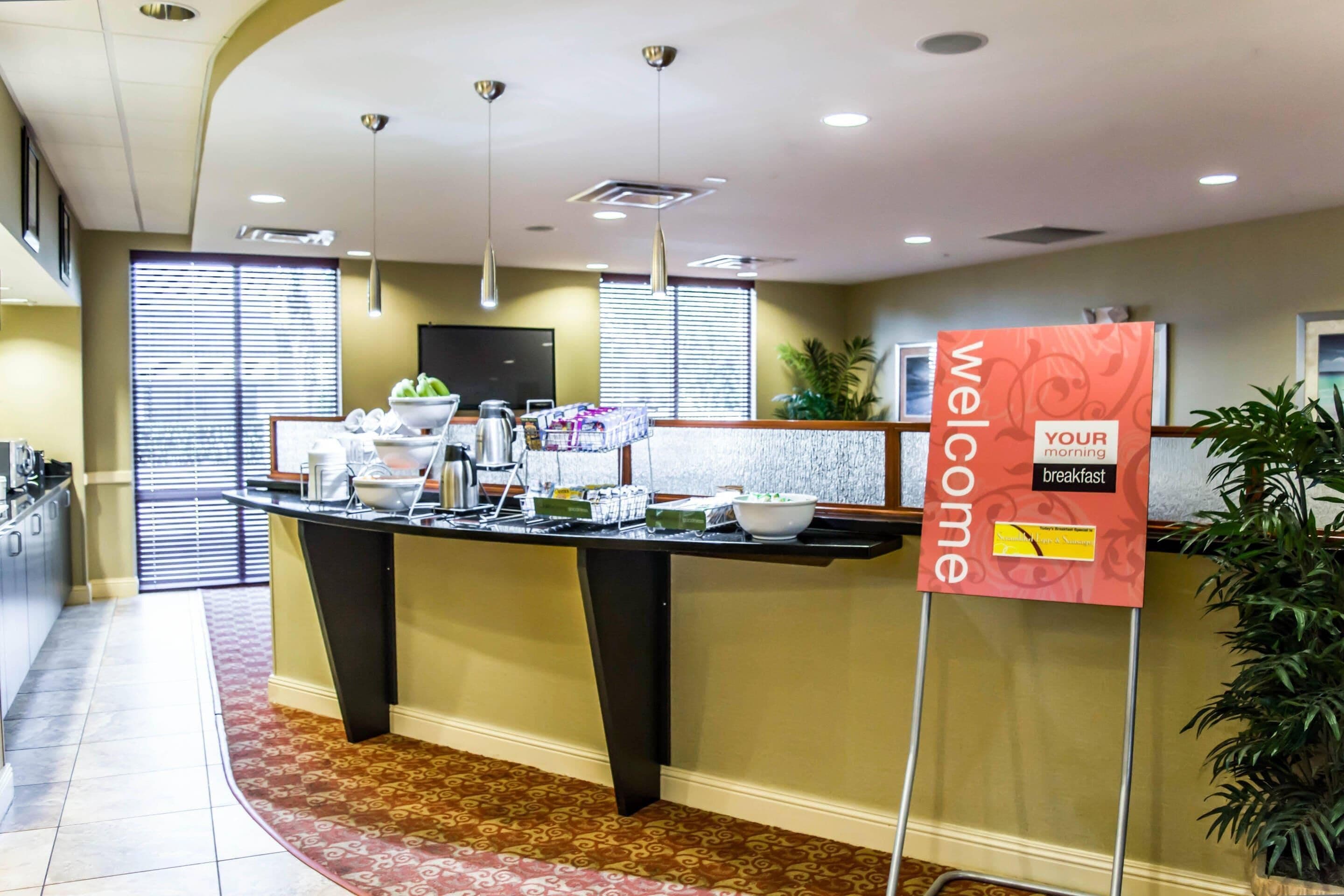 A reception area with a welcome sign, a buffet counter, and a potted plant.