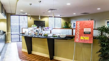 A reception area with a welcome sign, a buffet counter, and a potted plant.