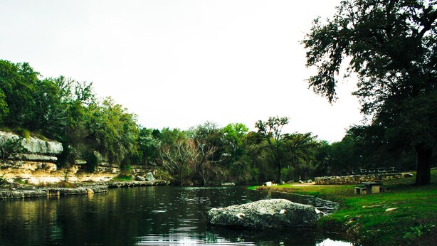 A natural landscape with a river, rocky cliffs, and dense greenery. - Flying L Ranch Resort (Bandera)