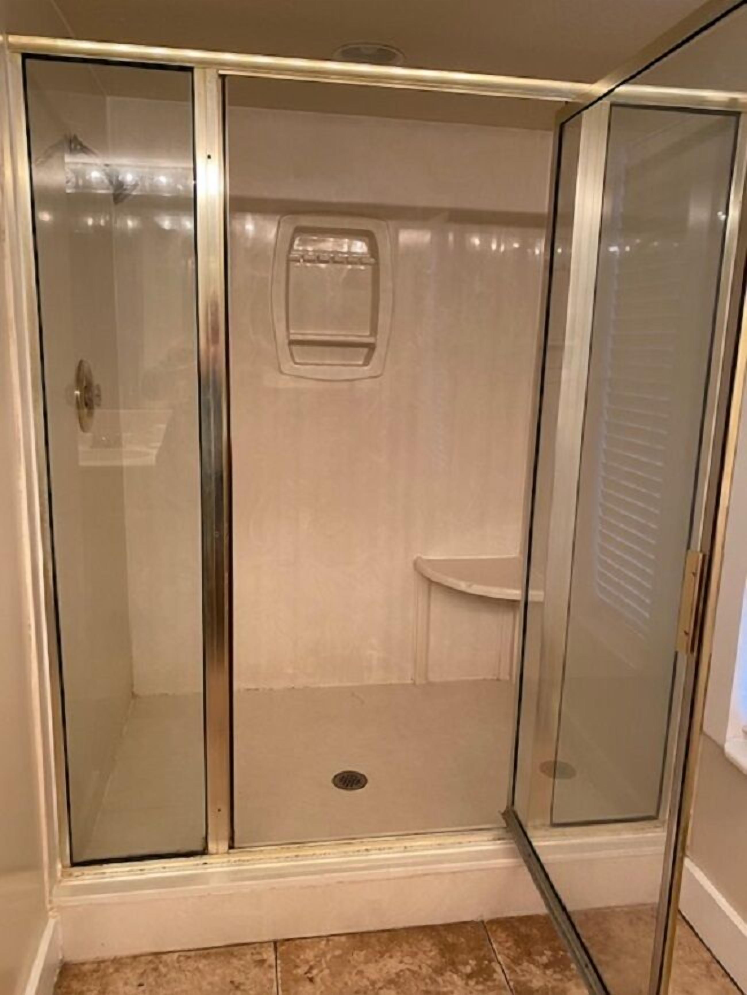 Une cabine de douche fermée par des parois en verre, dotée d’une porte, d’une petite fenêtre et de toilettes.