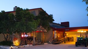 A building with a red roof, a sign that says "CHECK-IN", and a green tractor parked in front. - Flying L Ranch Resort (Bandera)