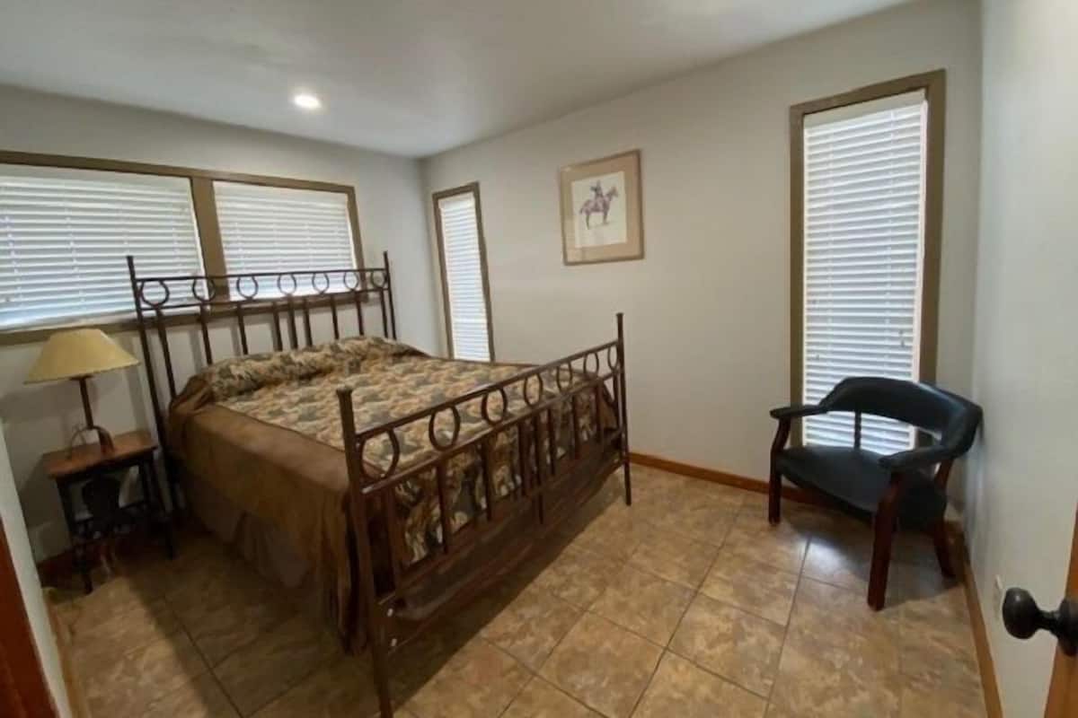 Un dormitorio con una cama, una silla y una ventana con persianas.