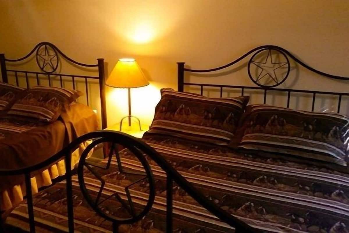 Una habitación con dos camas, cada una con cabecera en forma de estrella, lámpara de noche y ropa de cama estampada.