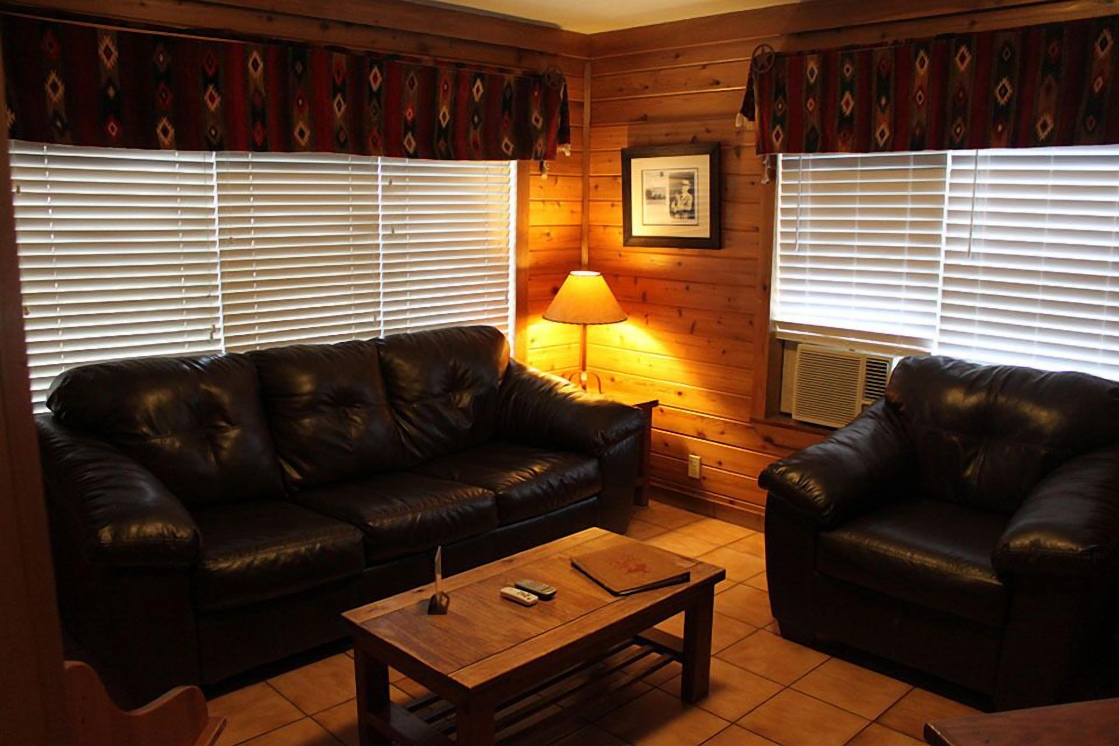 A cozy living room with a leather sofa, a wooden coffee table, and a lamp.