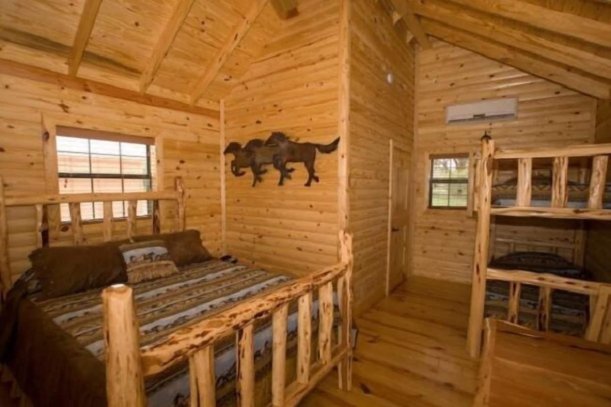 Una habitación tipo cabaña de madera con una cama, una ventana y un adorno en la pared.