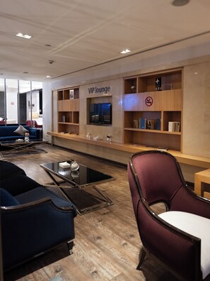 Un espace de détente moderne doté d’un téléviseur à écran plat, d’étagères en bois et de différents types de sièges.