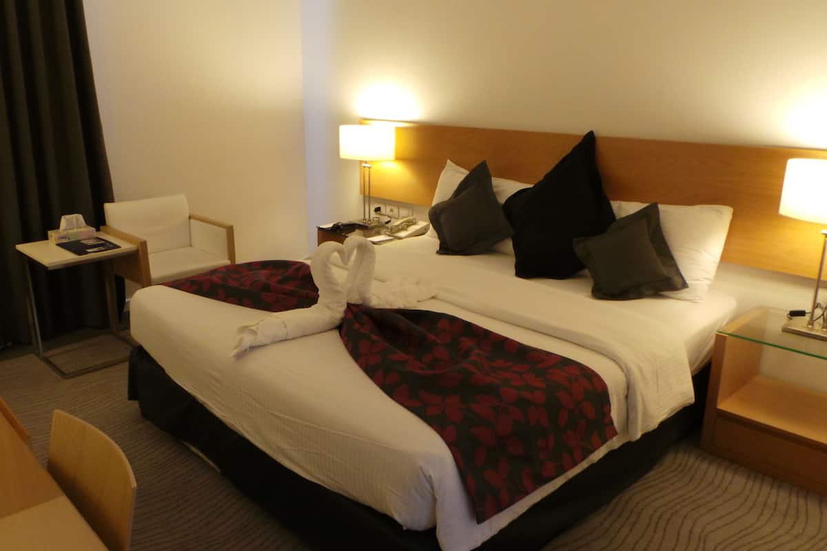 A hotel room with a large bed, two bedside tables, a desk, and a chair.