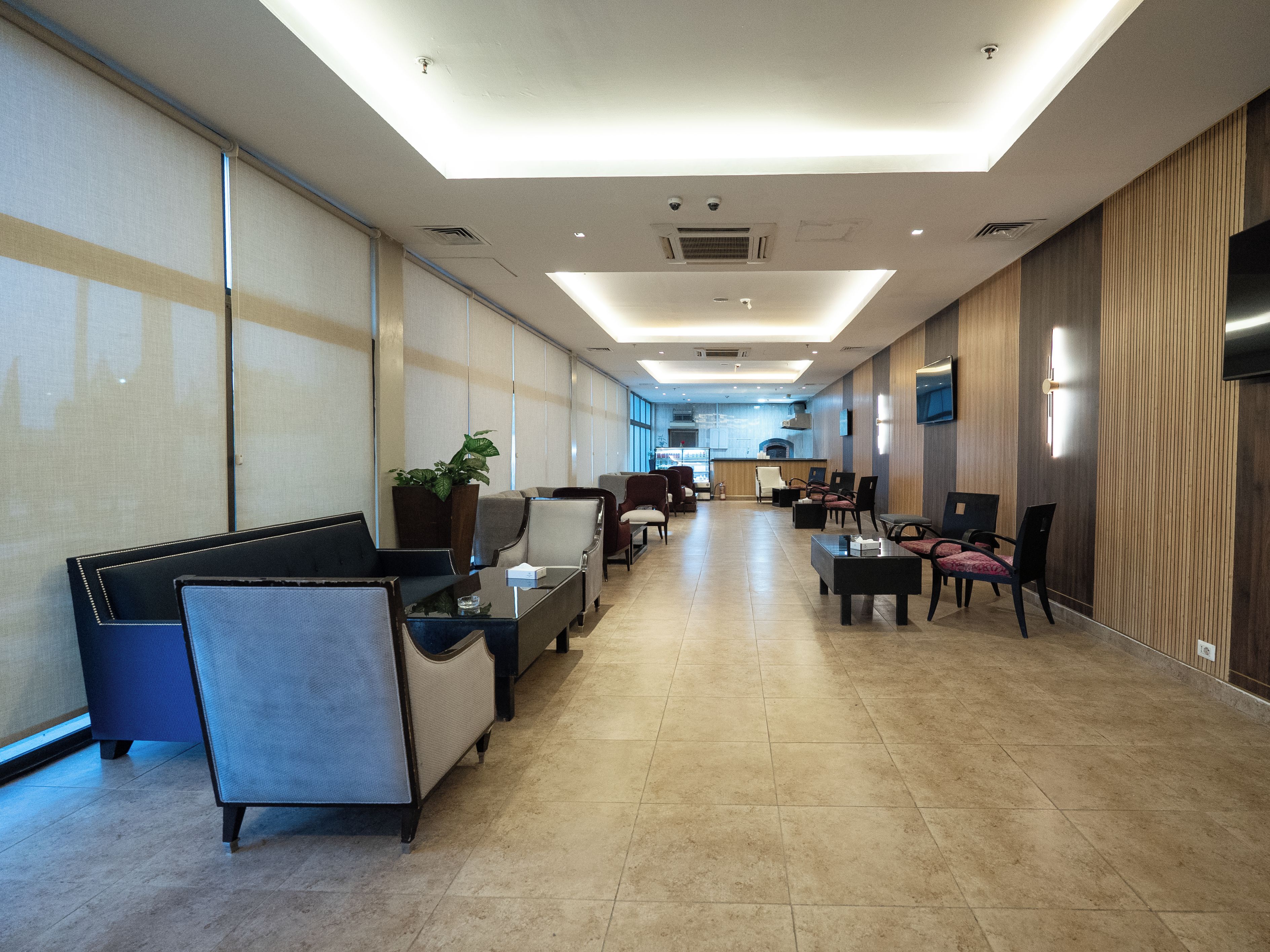 Un hall de hotel con zonas de estar, una recepción y una cocina al fondo.
