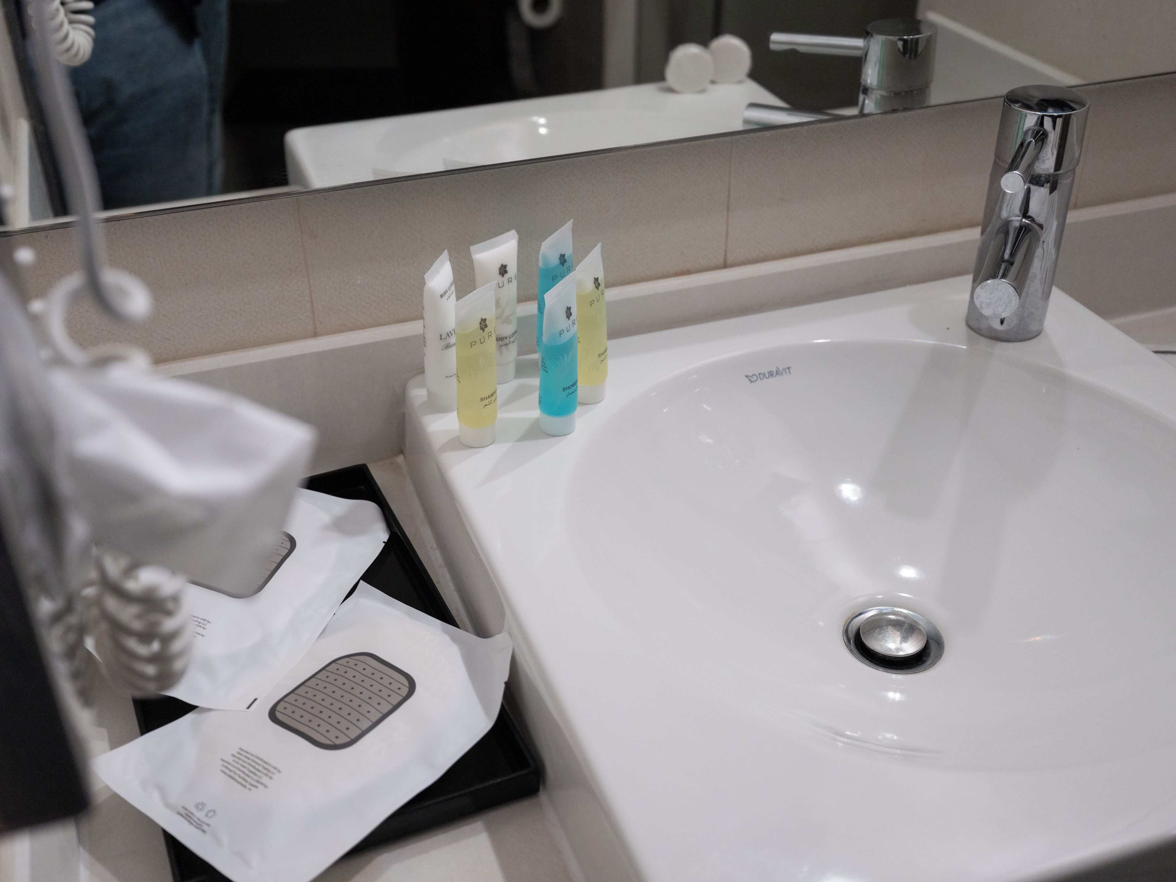 A bathroom sink with a mirror above it, a faucet, and several toiletries on the edge.