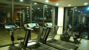 Un gimnasio con cintas de correr y elípticas, amplias ventanas y un diseño interior moderno.