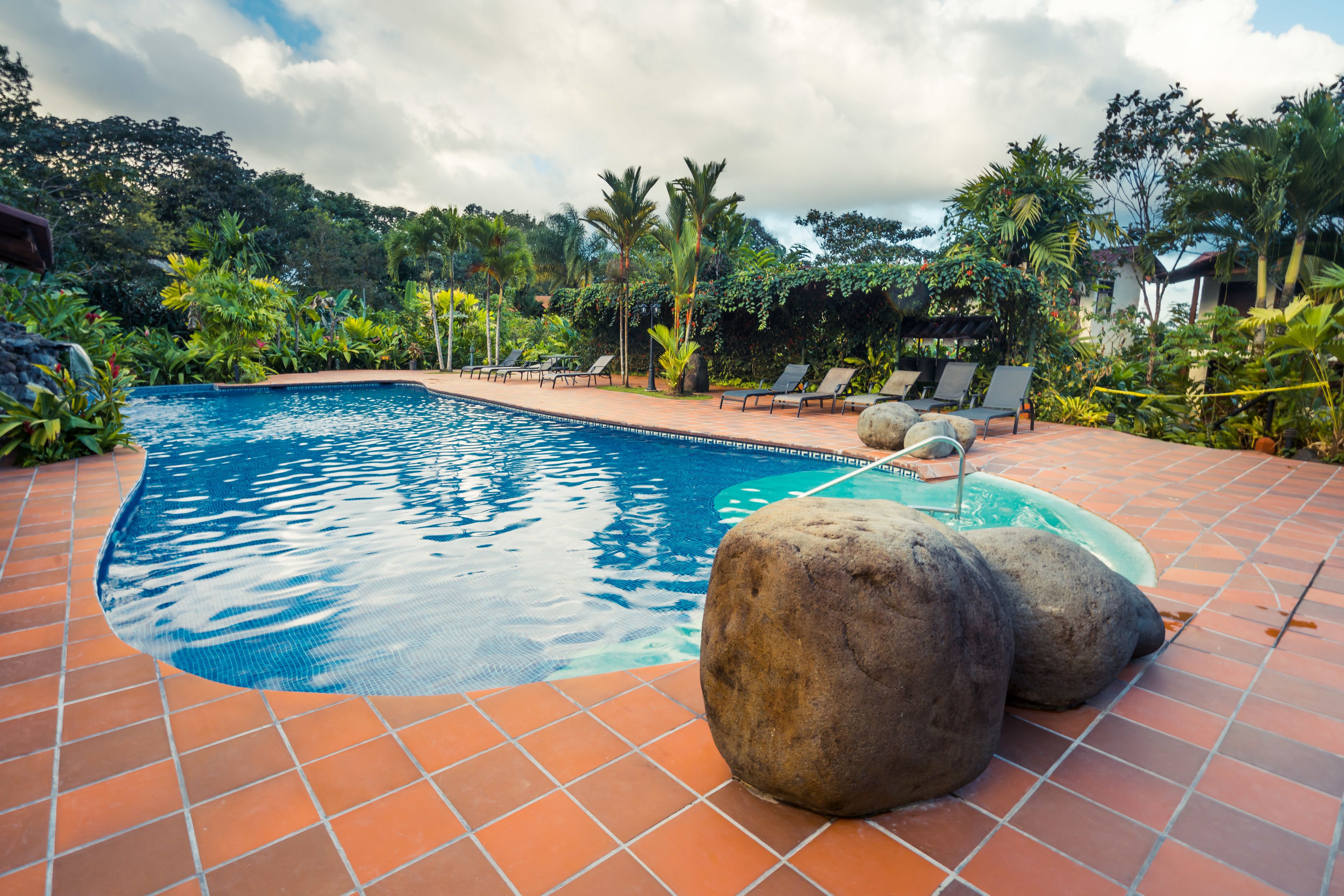 Una piscina al aire libre, sillones reclinables de piscina