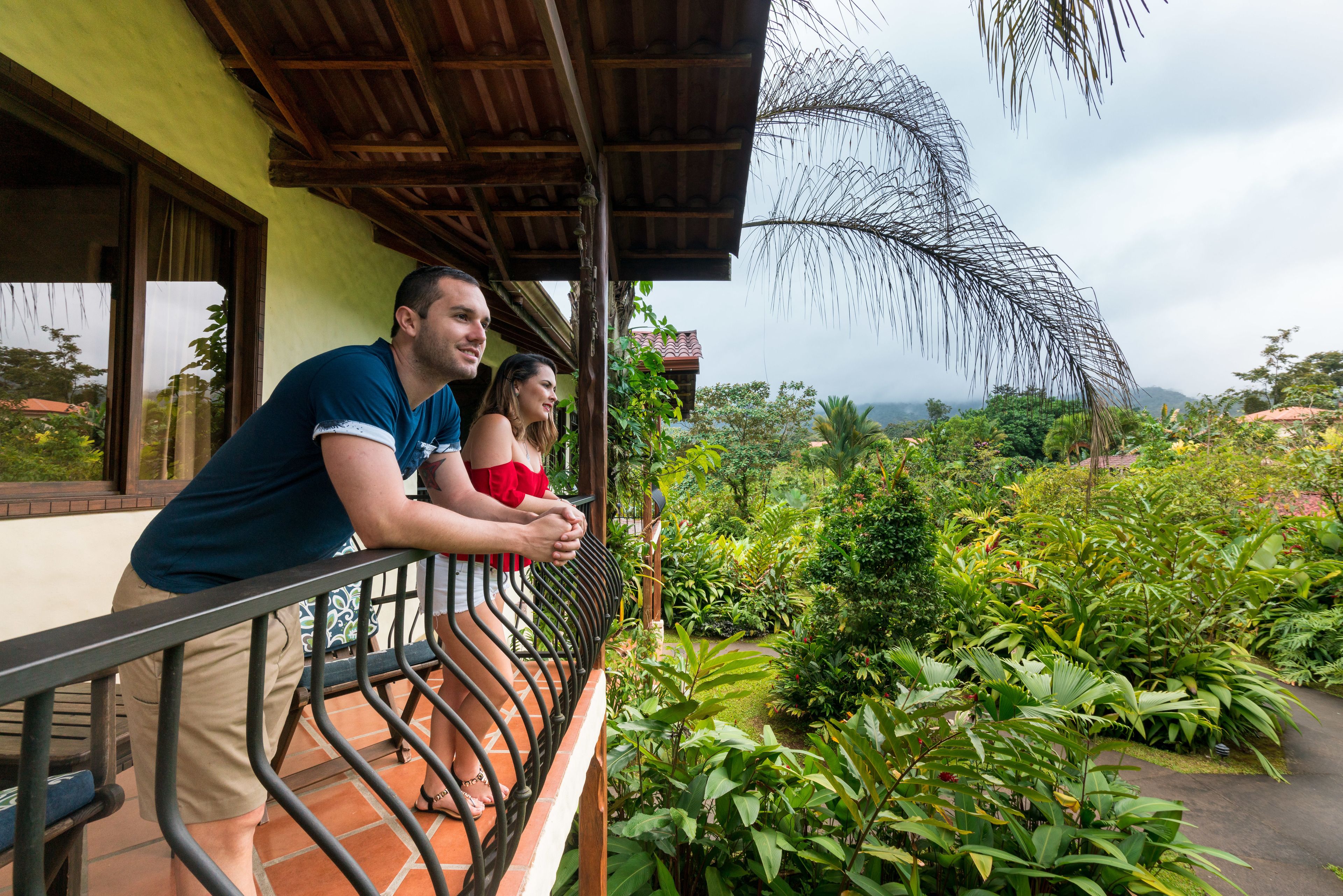 A balcony with a view of lush greenery and distant mountains.