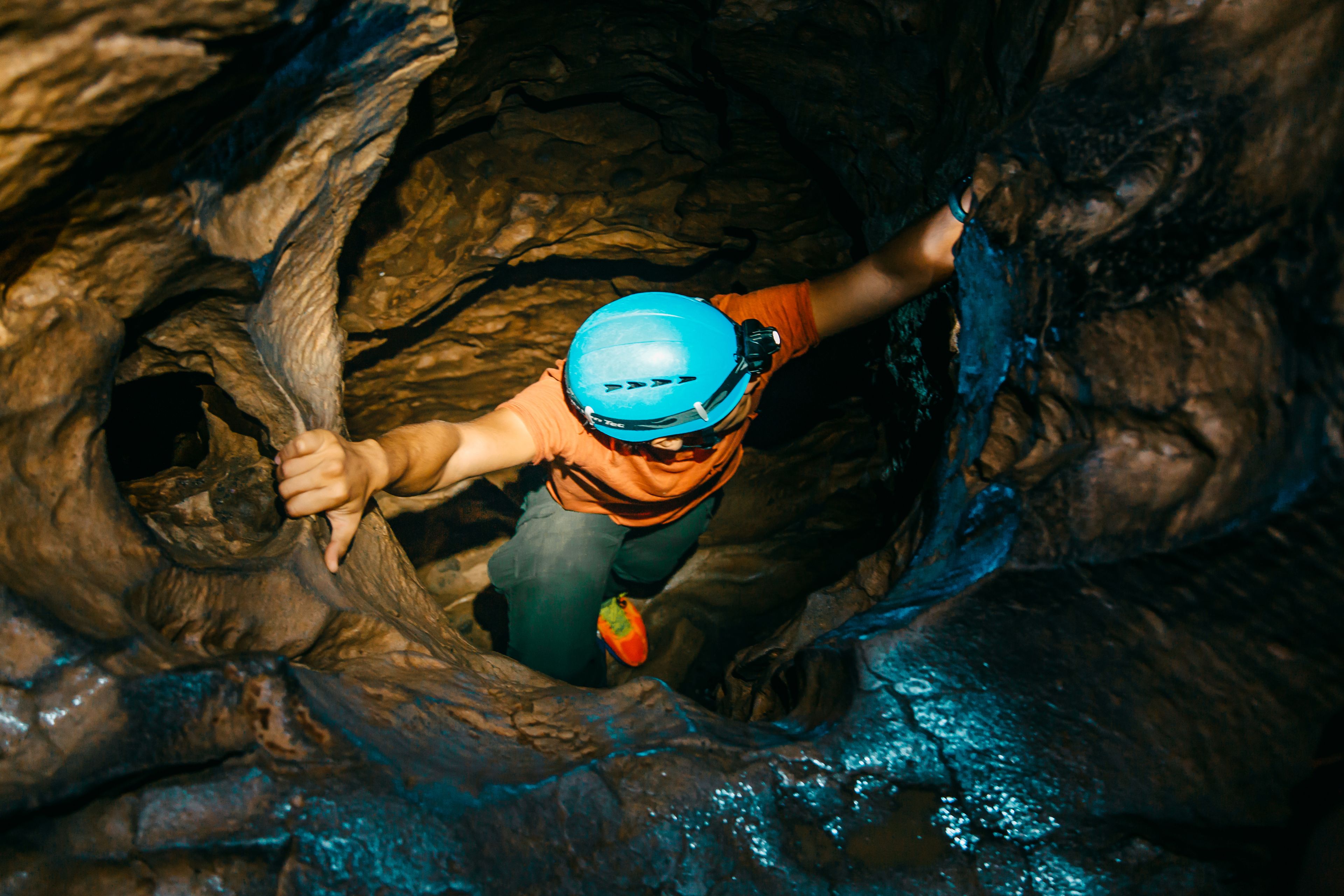 Eine Person seilt sich an einer felsigen Felswand in einer Höhle ab.