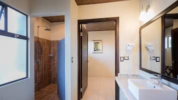 Un baño con ducha, lavamanos y un espejo grande.