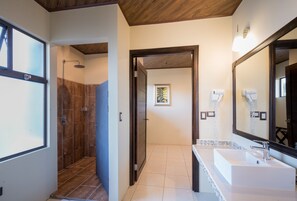 Un baño con ducha, lavamanos y un espejo grande.
