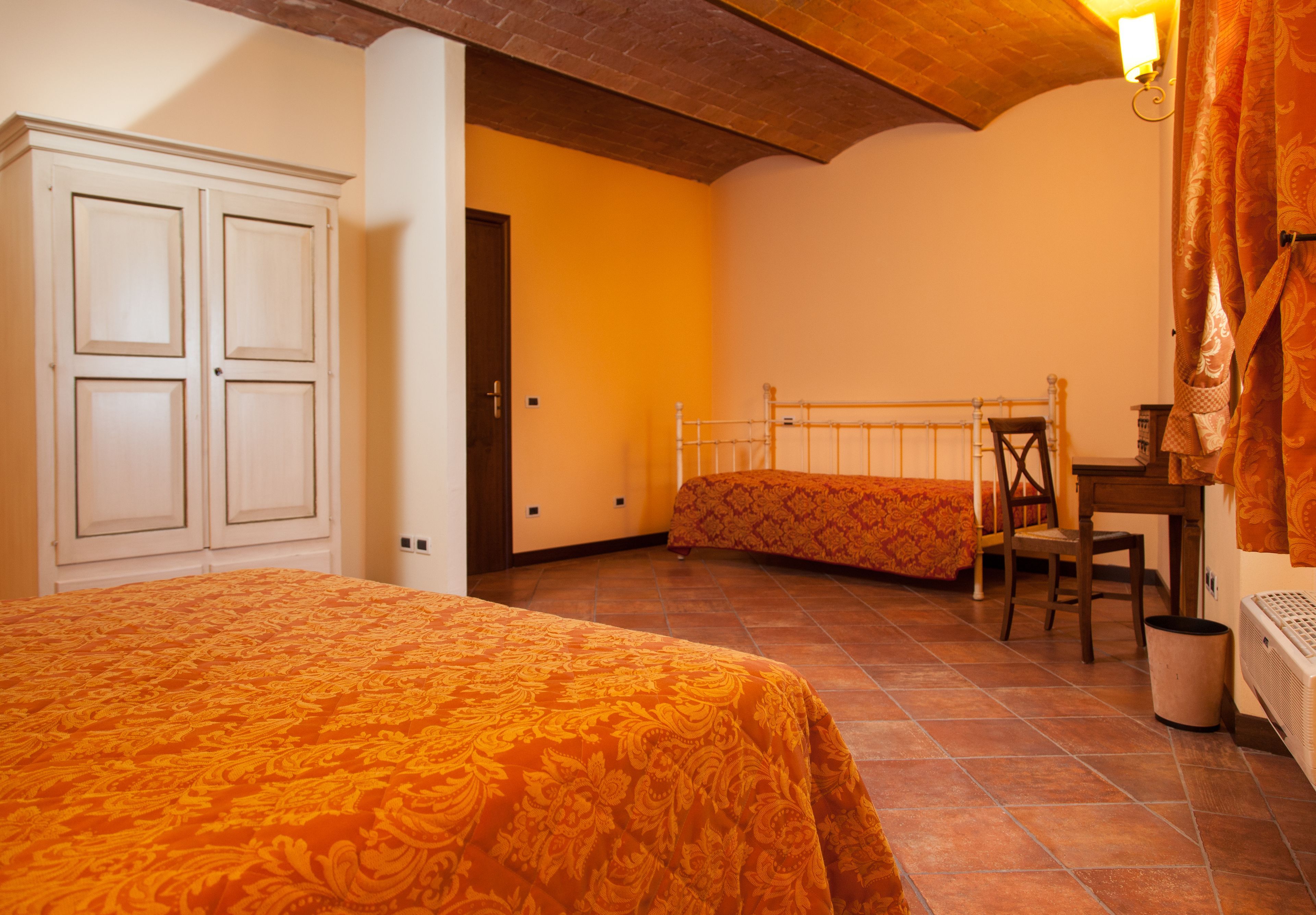 Une chambre à coucher avec un lit, un bureau et une chaise. On y trouve également une armoire et un radiateur.