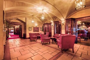 Un vestíbulo amplio con techos altos, candelabros ornamentales y una zona de bar.