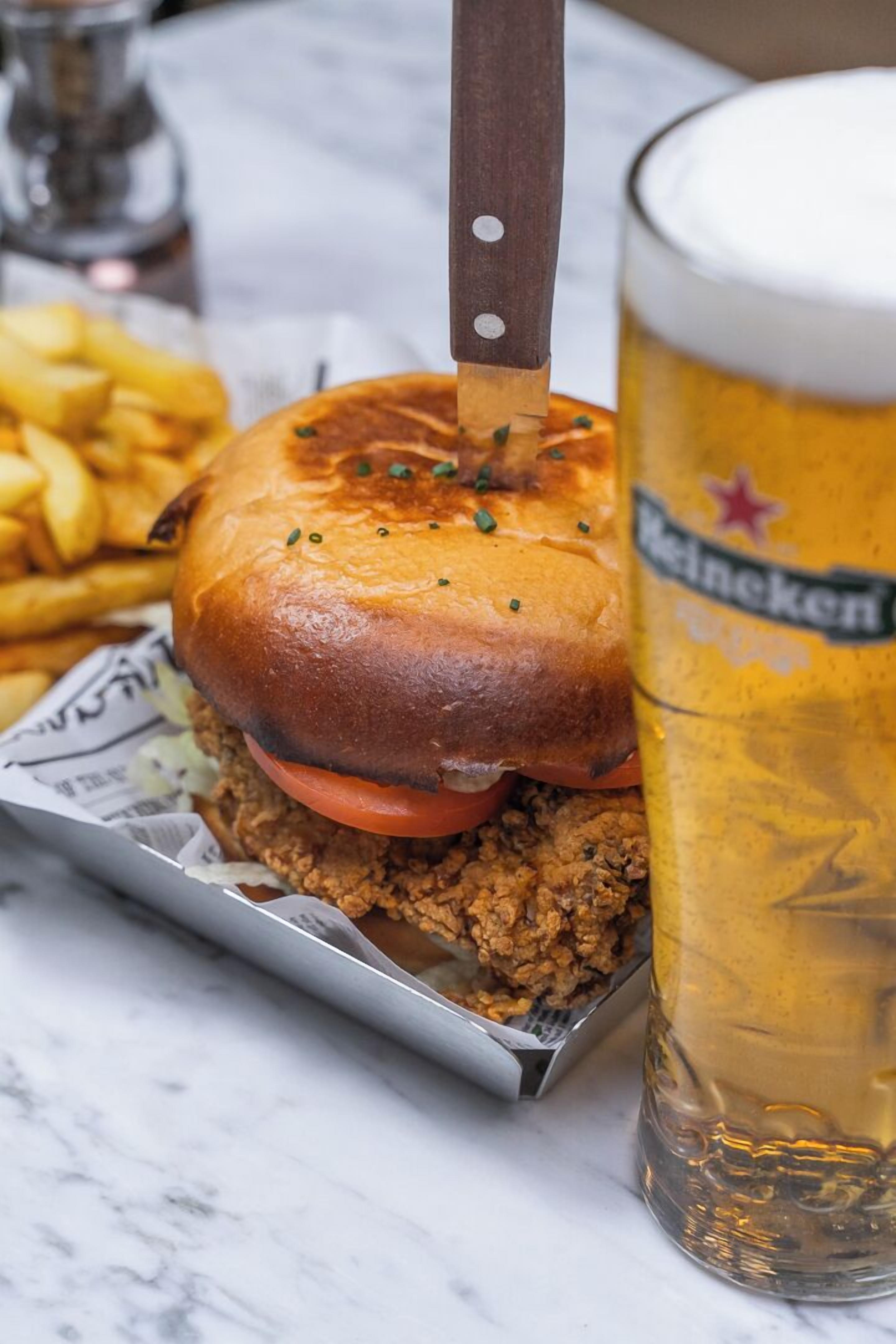 A meal consisting of a burger and fries, accompanied by a glass of beer.