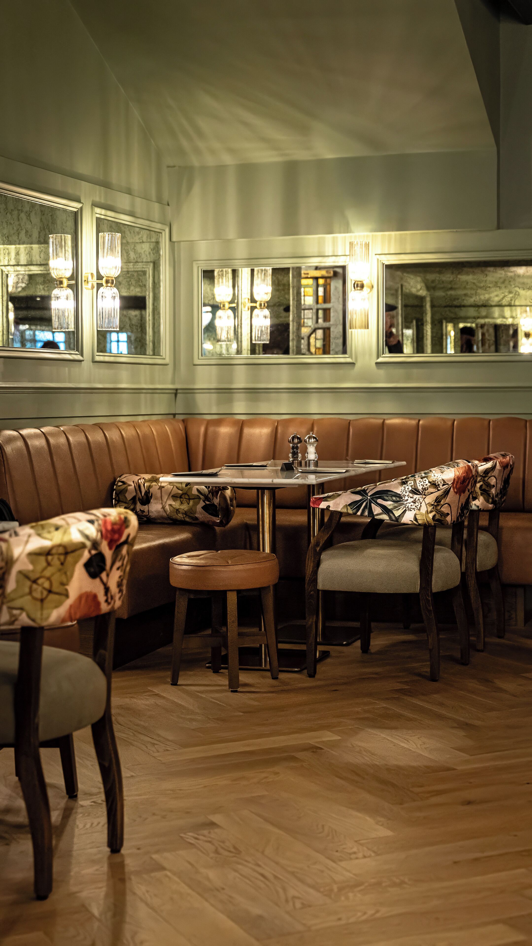 A dining area with a booth seating arrangement, a round table, and a bar area.
