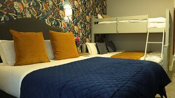 Quarto de hotel com cama beliche, um edredom azul acolchoado e papel de parede com padrão floral.