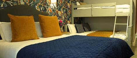 Habitación de hotel con literas, una colcha azul acolchada y un diseño de papel tapiz floral.