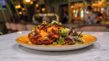 A plate of food with a crispy, golden-brown base topped with melted cheese and green onions, served on a white plate with a gold rim.