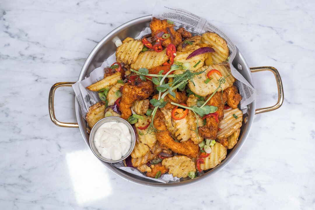 Un plato de pollo frito y verduras acompañado de salsa para mojar.