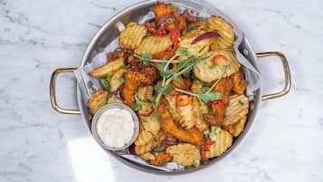 Un plato de pollo frito y verduras acompañado de salsa para mojar.