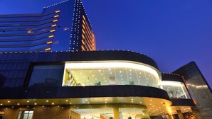 A modern hotel with a curved facade, large windows, and a prominent vertical tower in the background. - Dalian East Hotel (Dalian)