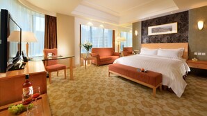 A hotel room with a large bed, a desk with a computer, a chair, and a sofa. - Dalian East Hotel (Dalian)