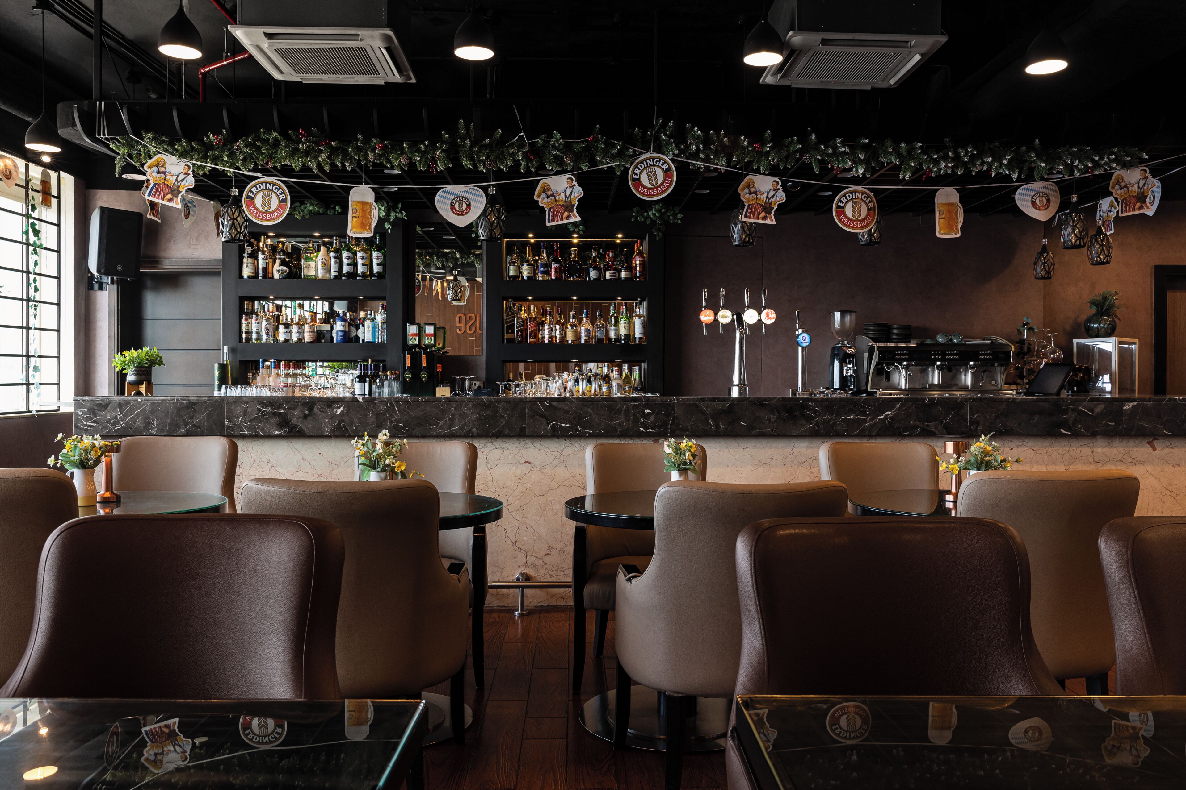 Zona de bar con asientos, barra con botellas y una máquina de café.