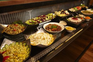 Ein Buffet mit verschiedenen Speisen, darunter Salate, Fleisch und Gemüse.