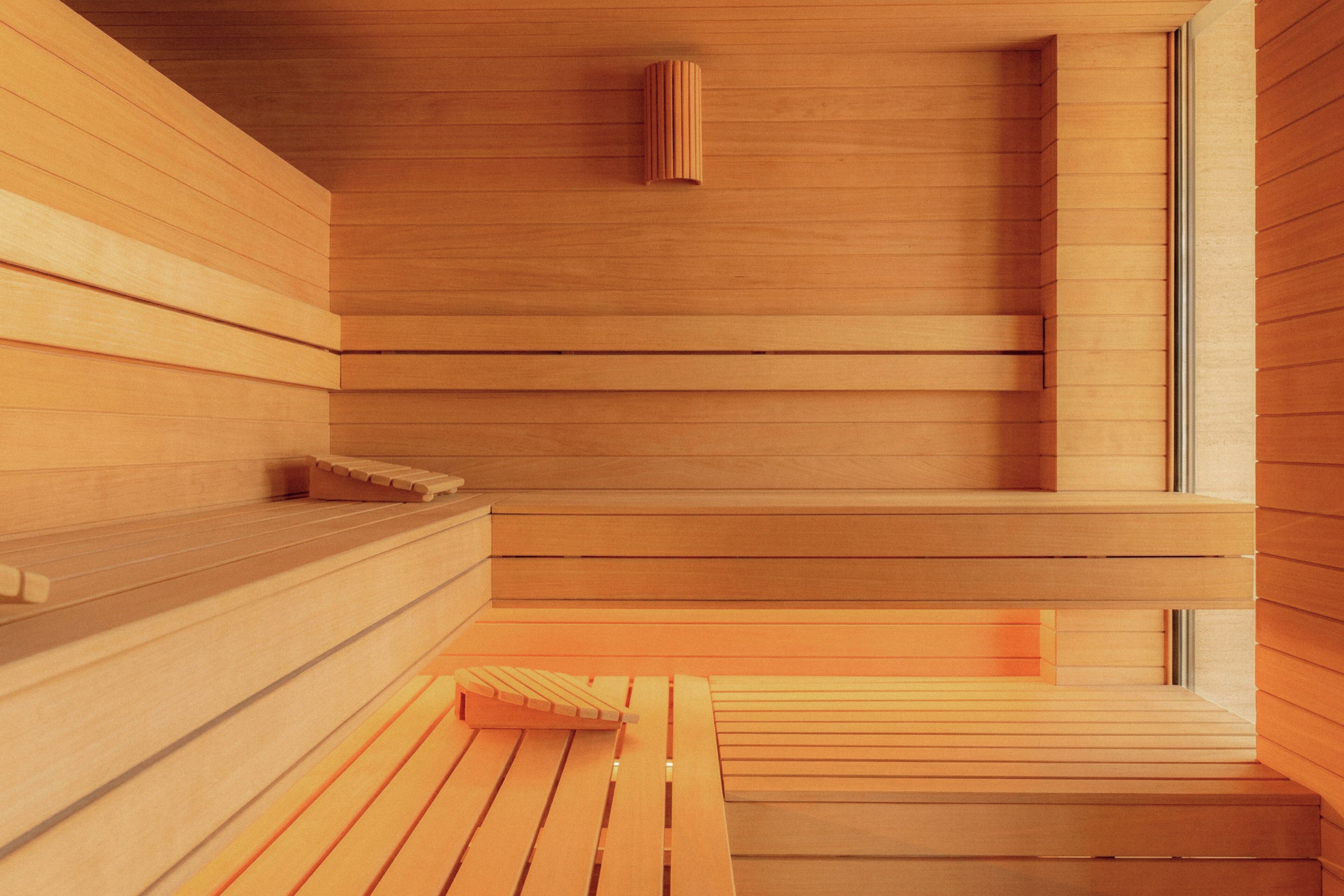 A wooden sauna with benches and a sloped ceiling.
