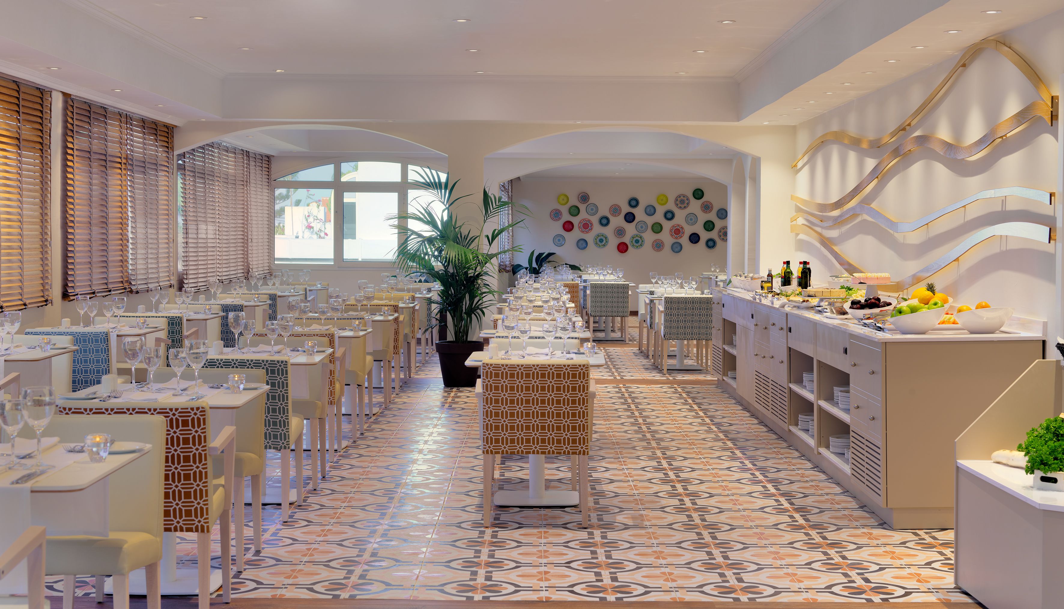 A restaurant with a long dining area, multiple tables, and a decorative wall with plates.