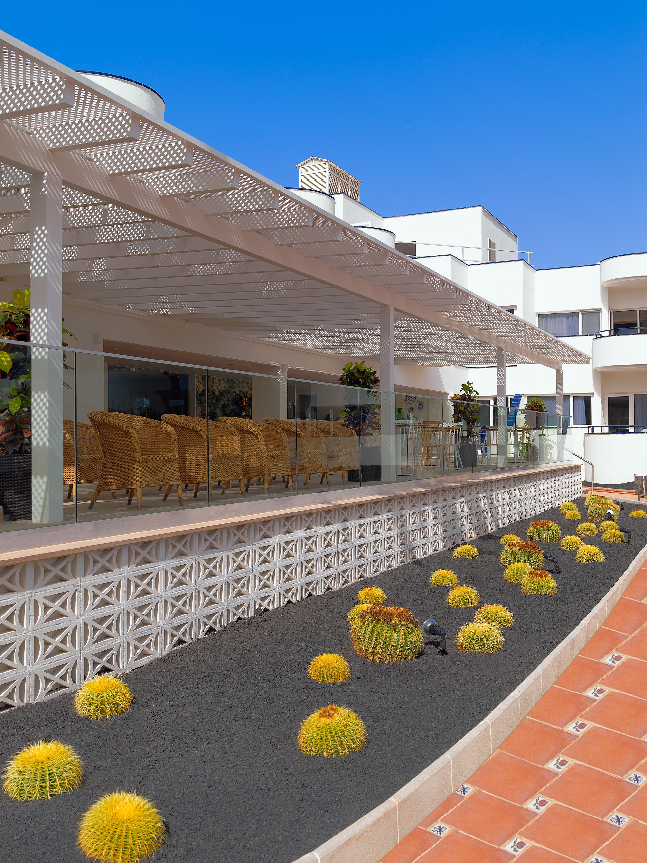 A modern outdoor seating area with wicker chairs and a white pergola.