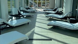 A sunroom with multiple lounge chairs, a glass ceiling, and a view of the outside. - The Towers Hotel and Spa (Neath)