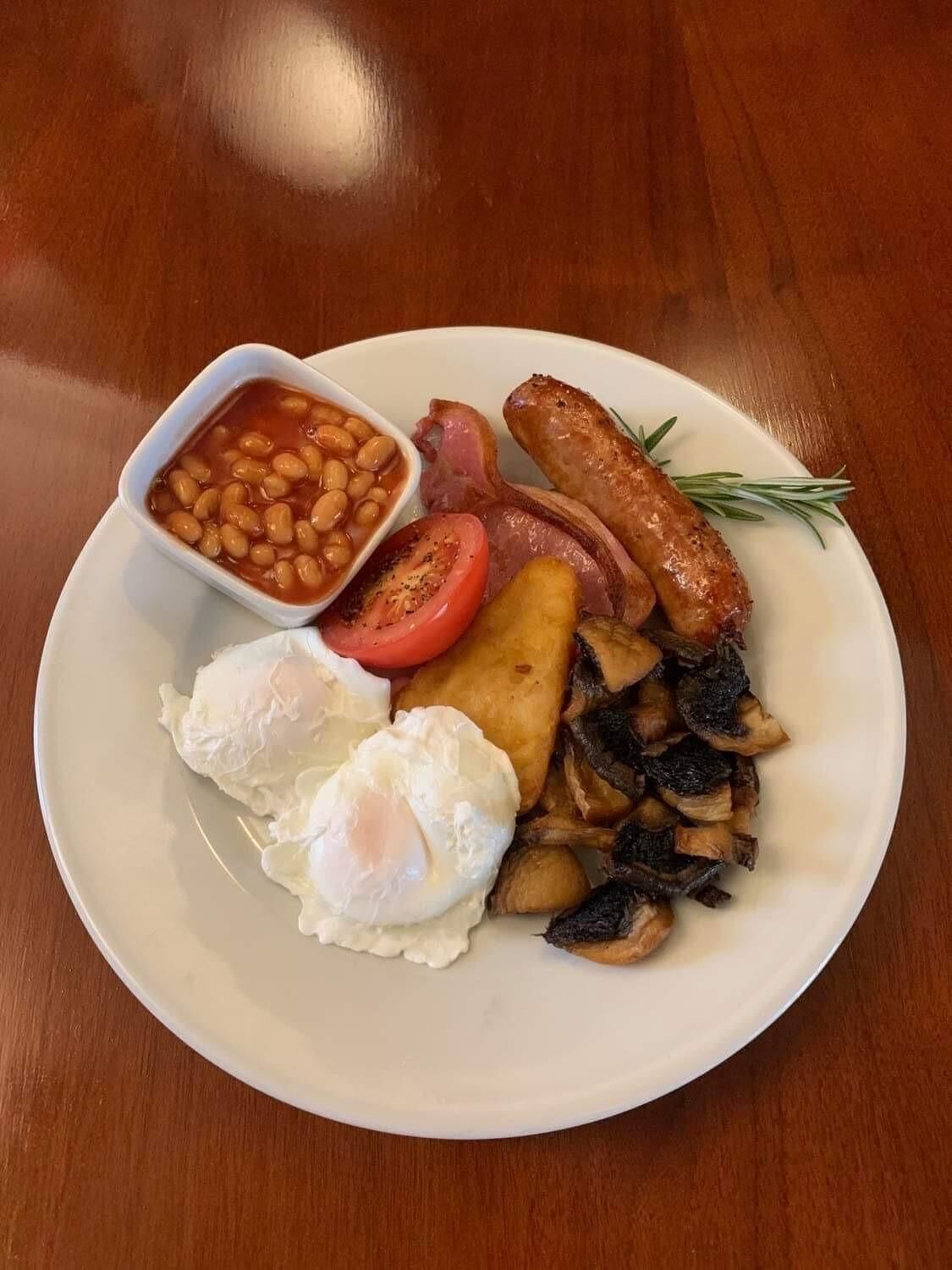 Prato de comida com feijão, linguiça, bacon, ovos e cogumelos.