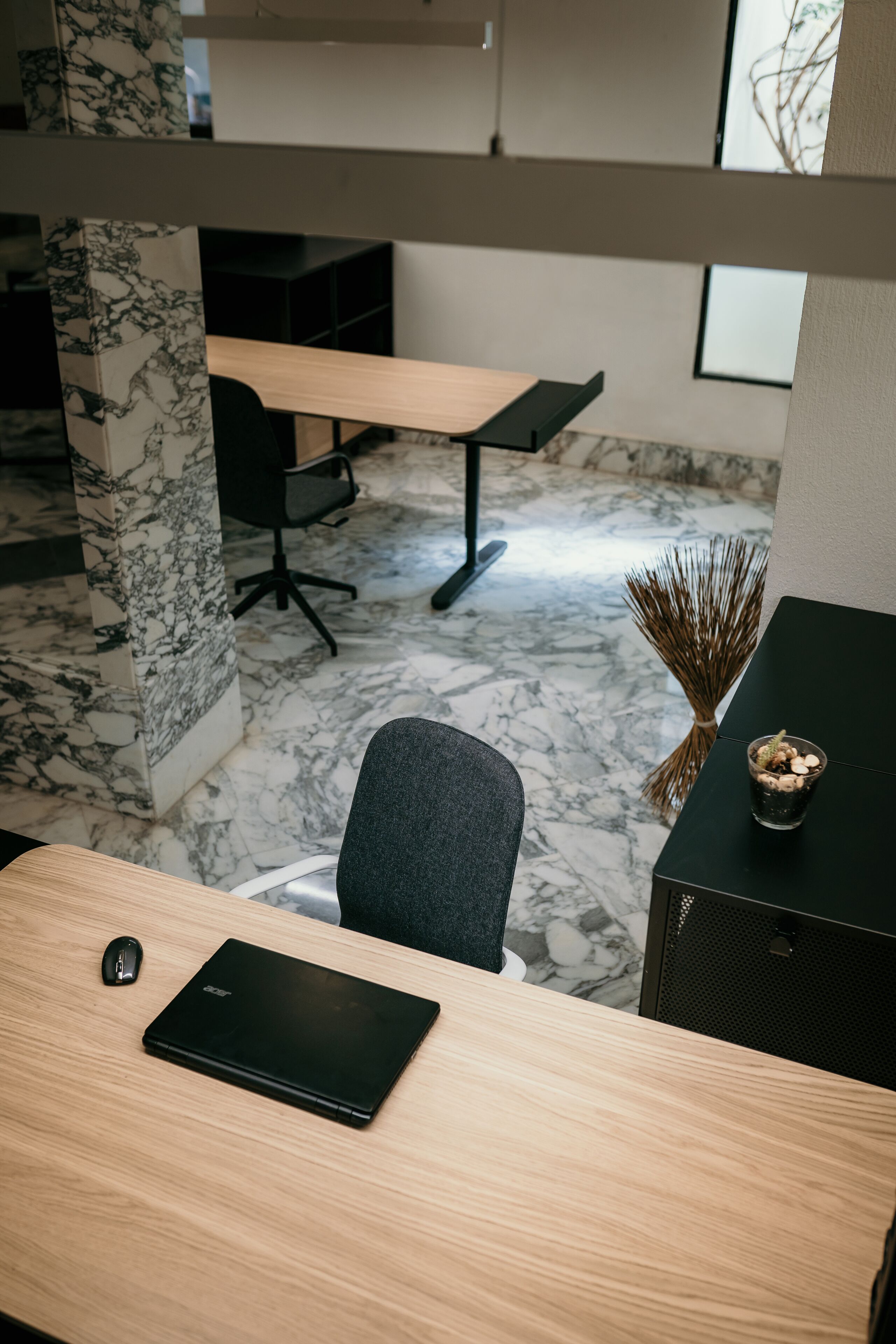 A modern office space with a wooden desk, a black laptop, and a black chair.