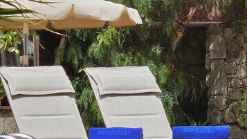 Un área junto a la piscina con sillones de descanso y una pared de piedra.