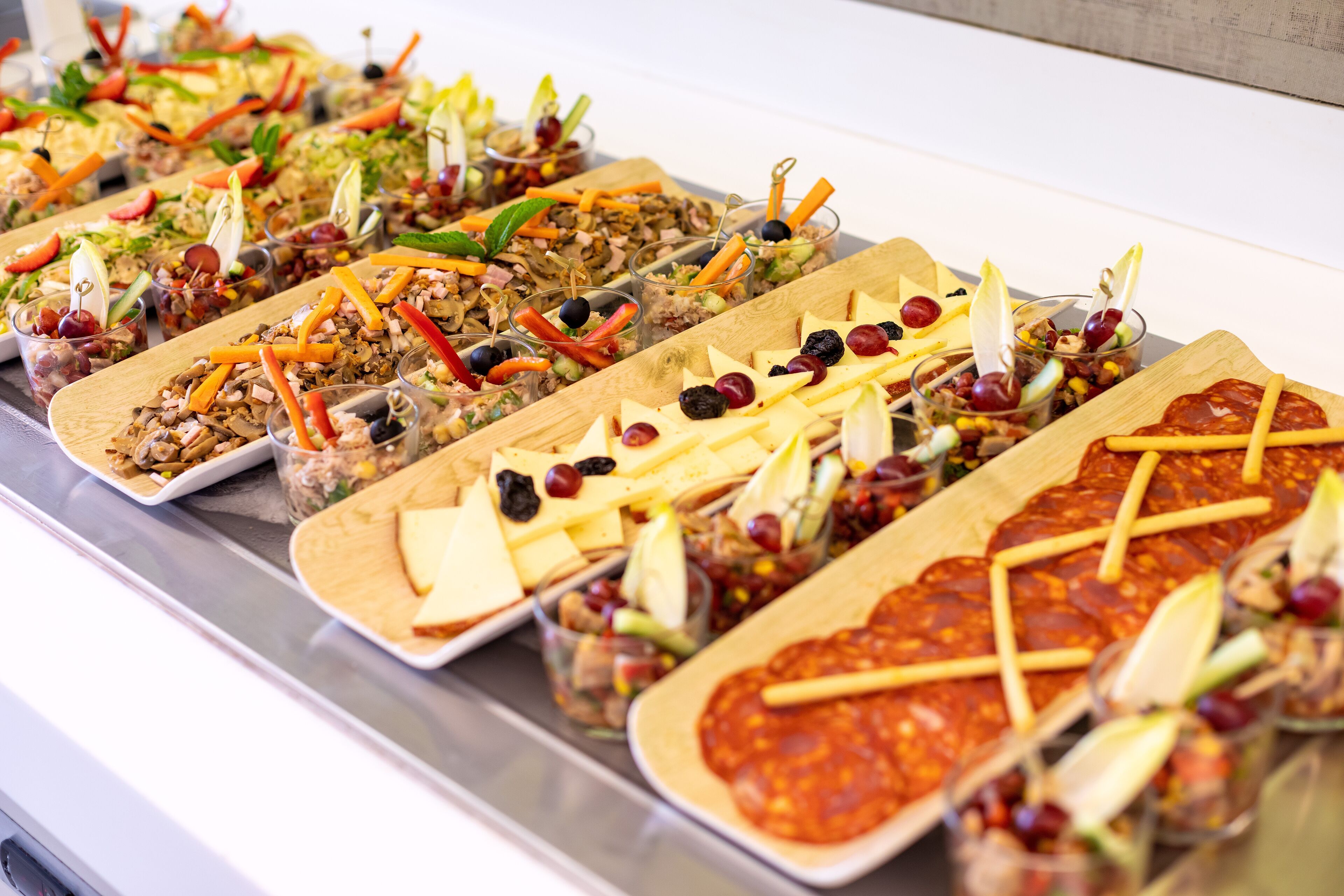 Un bufé con diversos platos, incluyendo ensaladas, carnes y quesos.