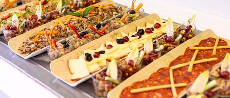 Un bufé con diversos platos, incluyendo ensaladas, carnes y quesos.