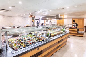 Zona de bufé con diferentes estaciones de comida y un chef preparando alimentos.