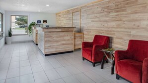 A reception area with a wooden reception desk, two red chairs, and a small table with a magazine.