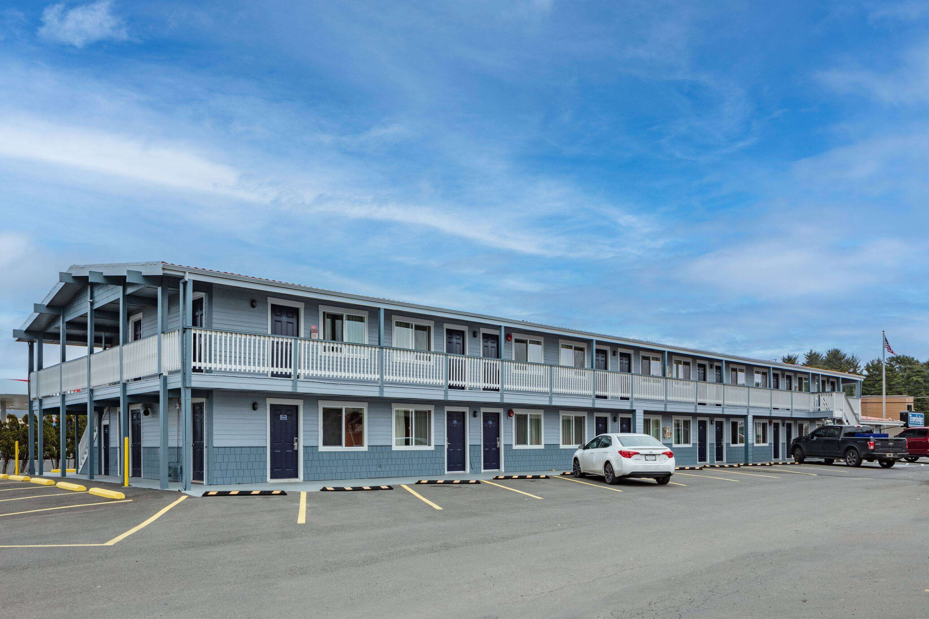 A motel with a two-story structure, multiple rooms, and a parking lot.