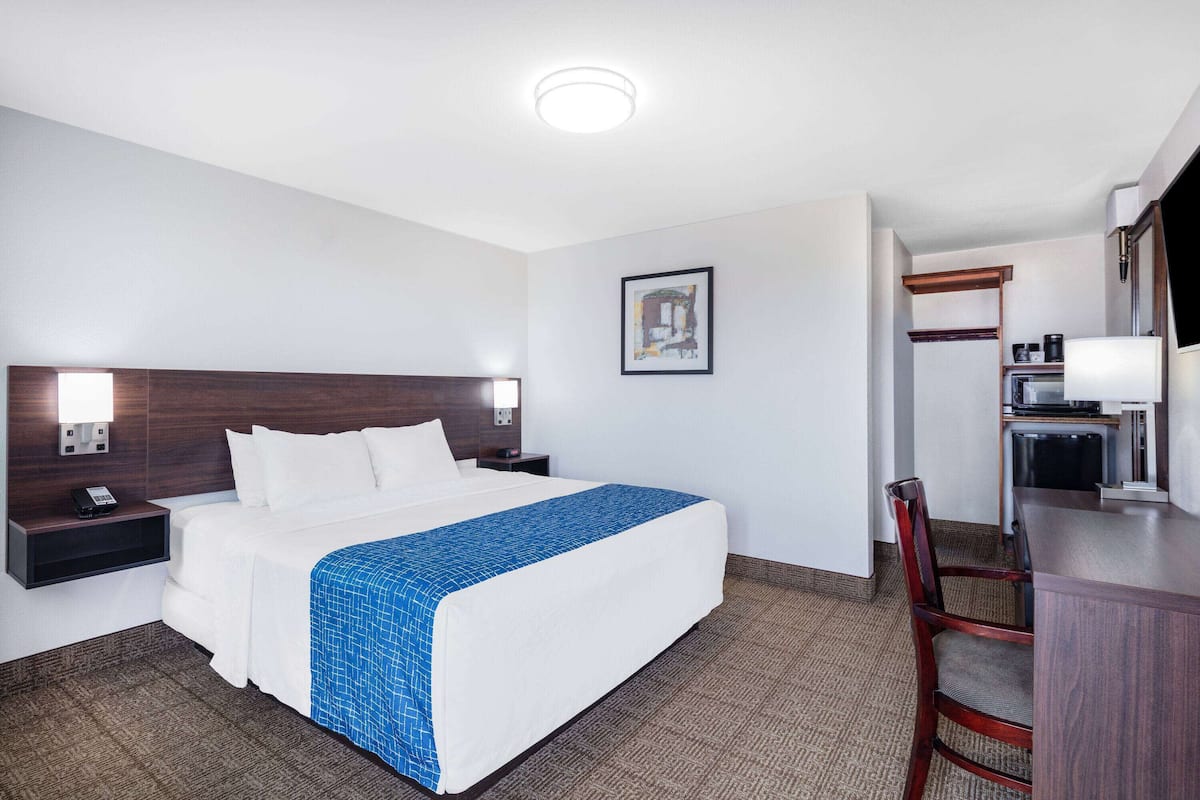 Une chambre d’hôtel comprenant un lit, des tables de chevet, un bureau, une chaise et une kitchenette.