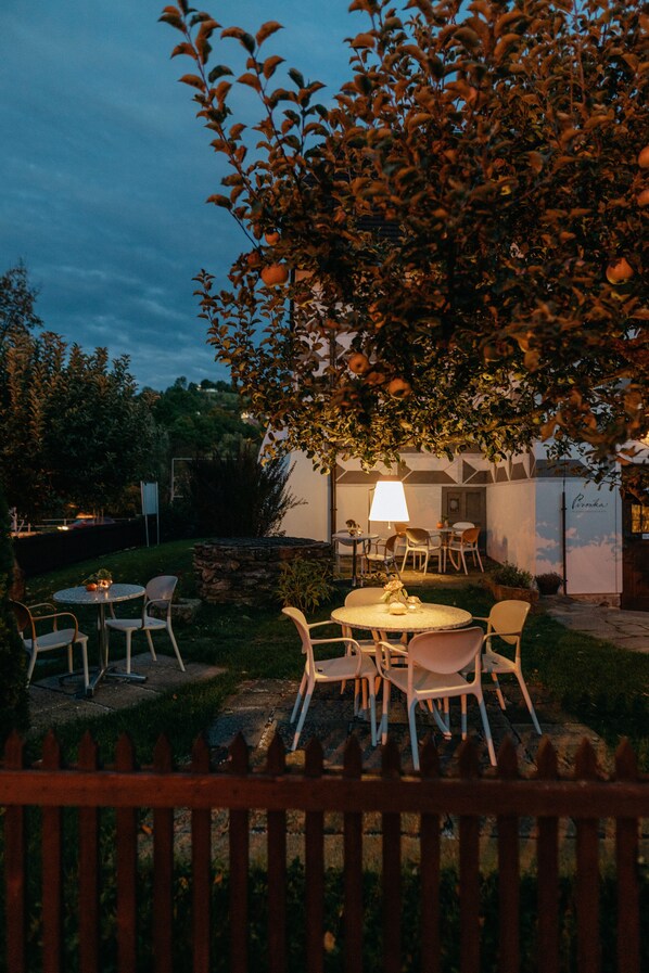 Un patio al aire libre con mesas y sillas redondas, una lámpara y un muro de piedra.